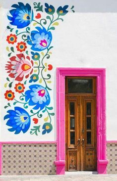 the door is decorated with colorful flowers and leaves on it's side, along with a pink window sill