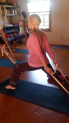 a woman is doing yoga on a mat in the middle of a room with other people