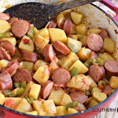 sausage and potatoes in a red pot with a wooden spoon