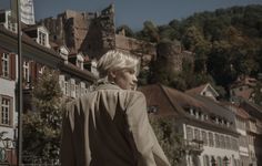 a young boy is walking down the street in front of some buildings and a castle