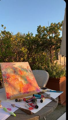 an artist's easel sitting on top of a table covered in art supplies