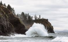 a large wave crashing into the ocean near a lighthouse