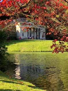 the house is surrounded by water and trees with red leaves on it's branches