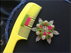 a yellow comb and brooch sitting on top of a black table next to a blue cloth