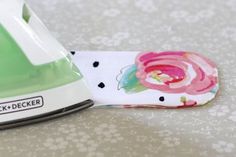 an ironing board with a flower on it next to a white and green hand towel