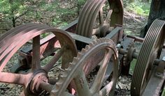 an old wooden wagon with two wheels on the ground next to a tree in the woods