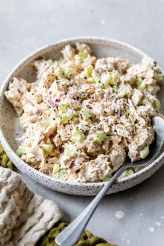 a bowl filled with chicken salad next to a pair of mitts and a napkin