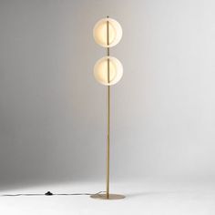 three light floor lamp in brass finish with white glass balls on the top and bottom