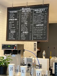 a menu hanging on the wall in a restaurant with cups lined up next to it