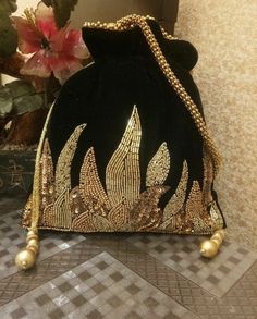 a black velvet purse with gold sequins and pearls on the bottom, sitting on a table