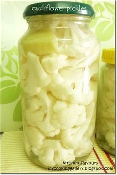 a jar full of cauliflower pickles next to another jar filled with it