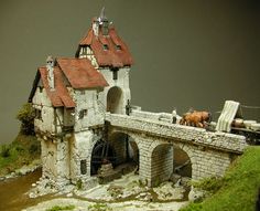 a miniature model of a castle with horses on the roof and water running under it