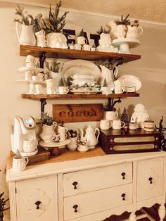 a white dresser topped with lots of dishes