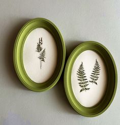 two green and white plates sitting on top of a table next to each other with plants drawn on them