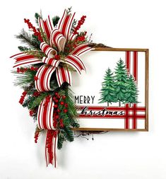 a red and white christmas wreath hanging on the wall next to a sign with merry christmas written on it