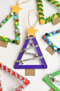 christmas tree ornaments made out of popsicle sticks and colored construction paper are displayed on a white surface