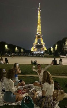 people sitting on the grass in front of the eiffel tower