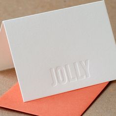 two folded cards with the word jolly printed on one side and an orange envelope in the other