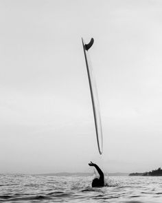 a person is in the water with a surfboard above their head while holding on to a pole