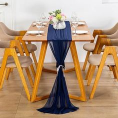 a wooden table topped with a blue cloth draped over it's top and surrounded by beige chairs