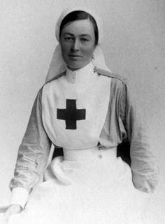 an old black and white photo of a woman in a nurse's outfit with a cross on it