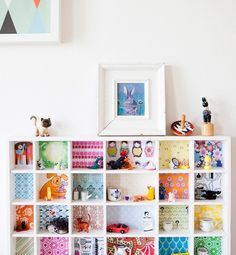 a white book shelf filled with lots of colorful books and toy figurines on top of it