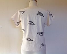 "Simple, boxy top made of 100% linen in white that has been block printed with a paper airplanes in black ink. Currently available in XS, S, M, L & XL Please choose size at checkout Size XS measures 37\" around the bust 38\" around the hem 21\" long Size Small measures 39\" around the bust 41\" around the hem 22\" from shoulder to hem Size Medium measures 42\" around the bust 44\" around the hem 23\" from shoulder to hem Size Large measures 45\" around the bust 47\" around the hem 25\" from White Hand Printed Crew Neck Top, White Hand Printed Short Sleeve Tops, Casual White Hand-printed Top, White Printed Everyday Tops, White Printed Tops For Everyday, Everyday White Printed Tops, Airplane Print, Boxy Top, Linen Tank Top