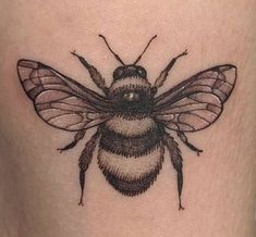 a black and white bee tattoo on the thigh