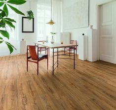 a dining room with wooden floors and white walls is seen in this image, there are two chairs at the table