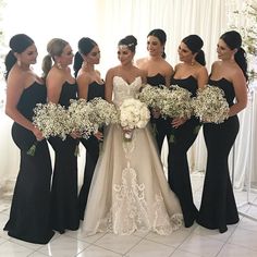 a group of women standing next to each other in front of a white wall holding bouquets