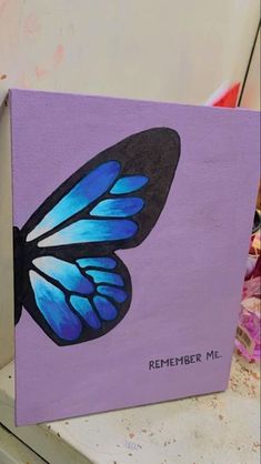 a painting of a blue butterfly on a purple background with the words, remember me