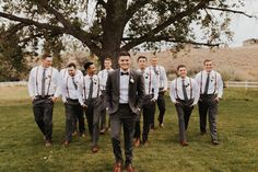 a group of men in suits and ties standing next to each other near a tree