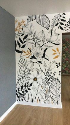 the wall is painted with black and white floral designs on it, along with wood flooring