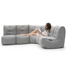 a woman sitting on top of a gray couch