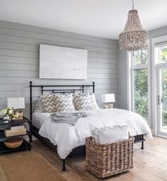 a bedroom with gray walls and white bedding, wicker baskets on the floor