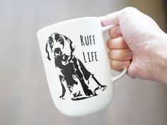 a person holding a coffee mug with a dog on it's side and the words ruff life printed on it