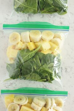 three plastic bags filled with different types of fruits and veggies on top of a marble counter