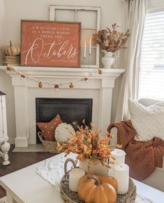 a living room decorated for fall with pumpkins, candles and other decorations on the fireplace mantel