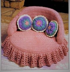 a pink crocheted chair with two pillows on it