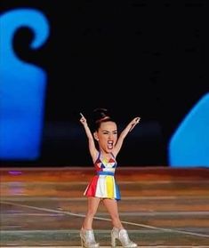 a woman is performing on stage with her arms in the air and one hand up