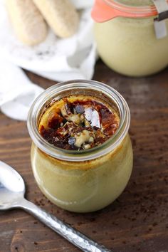 a jar filled with food sitting on top of a wooden table next to a spoon