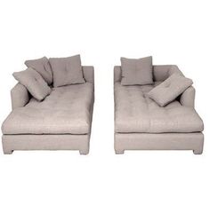 two couches with pillows sitting next to each other on a white background in front of a wall