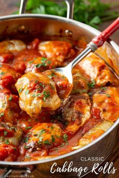 cabbage rolls with tomato sauce and parsley in a large metal pan on a wooden table