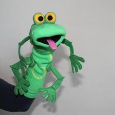 a person holding up a stuffed animal that looks like a frog with its tongue out