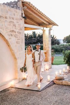 a bride and groom walking down the aisle with lit candles in front of their heads