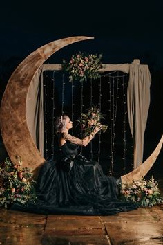 a woman is sitting on the moon with flowers in her hand and looking up at the sky