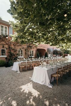 an outdoor dining area with tables and chairs set up for a formal function in front of a brick building