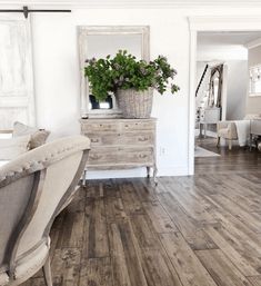 a bedroom with wood floors and white walls, has a large mirror on the wall