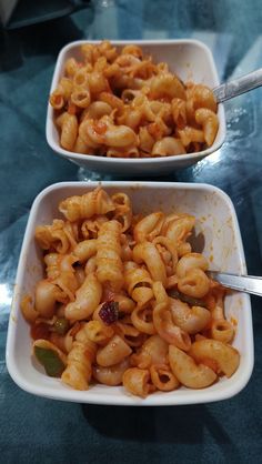 two white bowls filled with pasta on top of a table