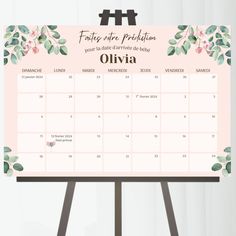 a desk calendar with flowers on it and the date in spanish is placed next to a easel